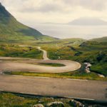 Shot of a young woman running on a long, winding road in the mountains